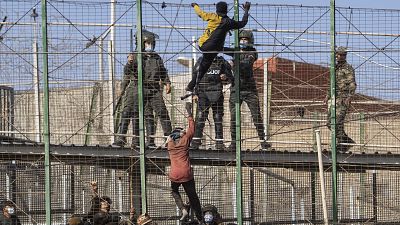 Migrants climb the fences separating the Spanish enclave of Melilla from Morocco in Melilla, Spain, Friday, June 24, 2022. 