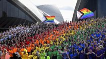 People make a human Progress Pride flag outside the Sydney Opera House