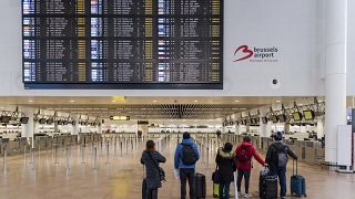 ركاب ينظرون إلى شاشة معلومات المغادرة وهم يقفون في صالة مغادرة مهجورة في مطار بروكسل - زفنتيم. 2019/02/13