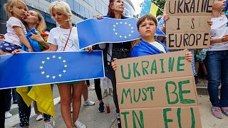 Protestors hold signs and EU and Ukrainian flags during a demonstration in support of Ukraine outside of an EU summit in Brussels.