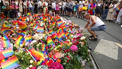 Des personnes déposent des fleurs sur les lieux d'une fusillade près d'un club gay dans le centre d'Oslo, en Norvège, samedi 25 juin 2022.
