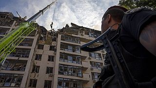 Katasztrófavédelmi szakemberek takarítják el a romokat a 2022. június 26-i kijevi rakéta támadás után