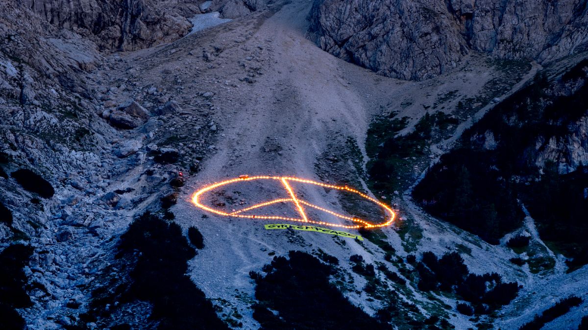 A Greenpeace üzenete a világ vezetőinek, égő fáklyák az Alpokban.