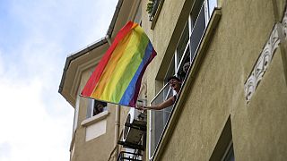 Женщина размахивает радужным флагом из окна дома во время гей-парада в Стамбуле. 26 июня 2022 г.