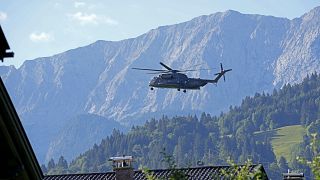 طائرة هليكوبتر تحلق منتجع شلوس إلماو فوق سفوح جبال الألب البافارية، ألمانيا.