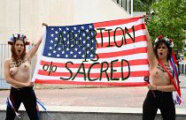 Активистки Femen держат американский флаг с надписью "Аборт священен"