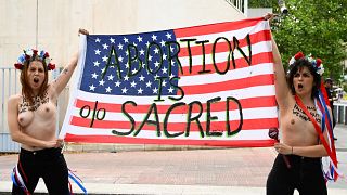 Активистки Femen держат американский флаг с надписью "Аборт священен"