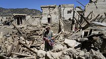 Un homme tenant un bébé au milieu de maisons en ruines dans la proivince de Paktika (26/06/2022)