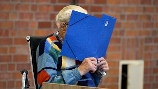 Josef S. covers his face as he sits at the court room in Brandenburg, Germany, Thursday, Oct. 7, 2021