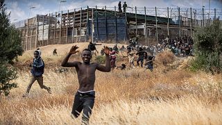 Migrants run on Spanish soil after crossing the fences separating the Spanish enclave of Melilla from Morocco in Melilla, Spain, Friday, June 24, 2022