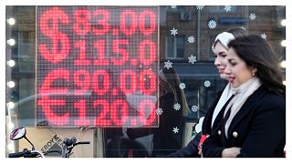 سبدتان أمام شاشة مكتب صرف العملات التي تعرض أسعار صرف الدولار الأمريكي واليورو إلى الروبل الروسي وسط مدينة موسكو