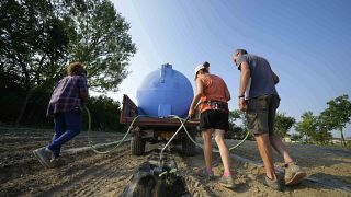 Gli agricoltori irrigano un campo di zucche utilizzando una pompa di sollevamento dell'acqua vicino al fiume Po a Guastalla, Italia, mercoledì 15 giugno 2022.