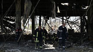 Des sauveteurs marchent dans le centre commercial détruit à Krementchouk