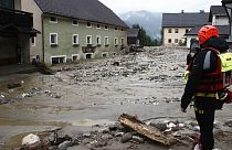 Rescue workers stand among damaged houses after heavy rain in Treffen.
