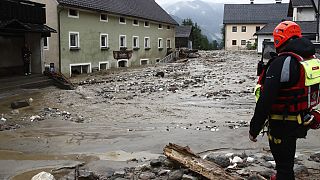 Rescue workers stand among damaged houses after heavy rain in Treffen.