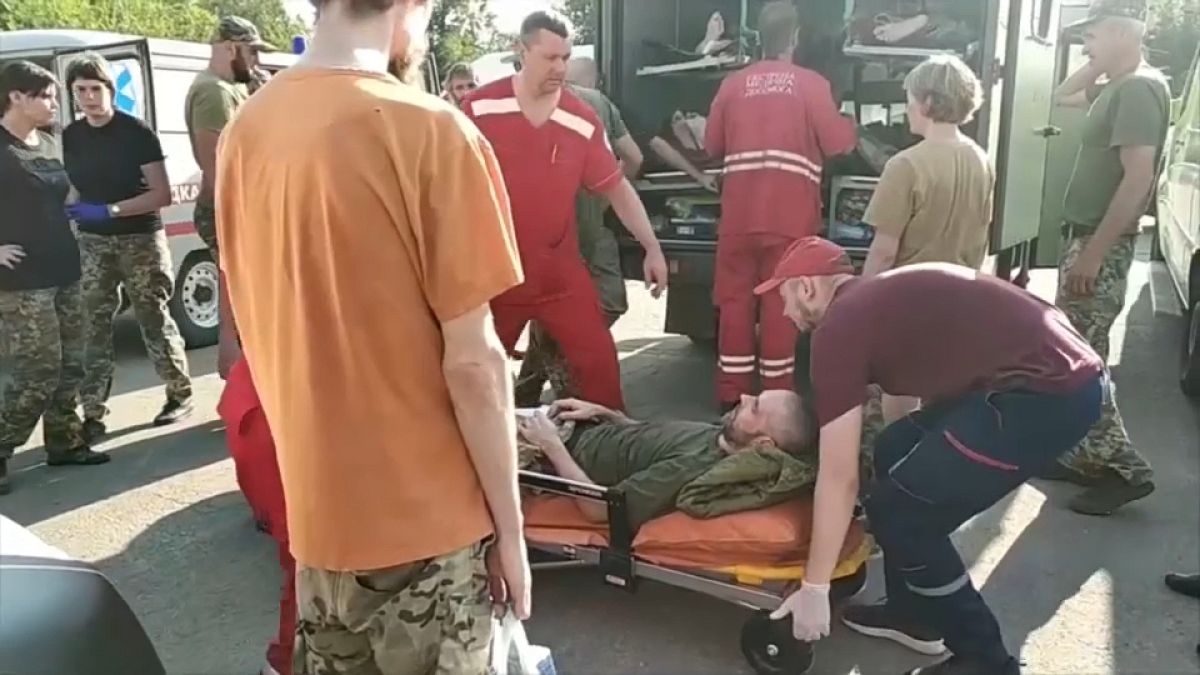 An injured Ukrainian prisoner being handed over on a stretcher