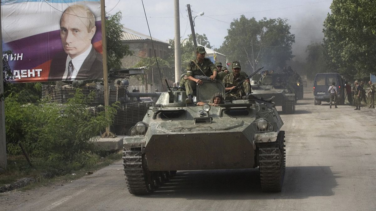 Ossetian soldiers on top of a tank enter Tskhinvali in the Georgian breakaway enclave of South Ossetia as they pass a giant portrait of Russia's Vladimir Putin in August 2008