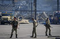 Ukrainian soldiers stand in front of a shopping center burned after a rocket attack in Kremenchuk, 28 June 2022