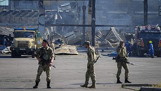 Ukrainian soldiers stand in front of a shopping center burned after a rocket attack in Kremenchuk, 28 June 2022