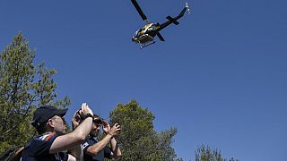Firefighters from EU-funded Rescue mission take video as an Augusta firefighting helicopter flies over them during a training session to prevent and fight wildfires