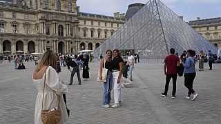 Touristinnen posieren vor dem Louvre im Paris am 20. Juni 2022