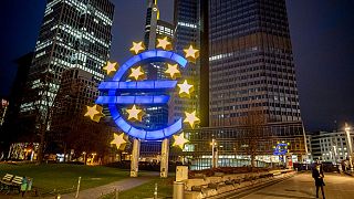 In this Thursday, March 11, 2021 file photo, a man walks past the Euro sculpture in Frankfurt, Germany.