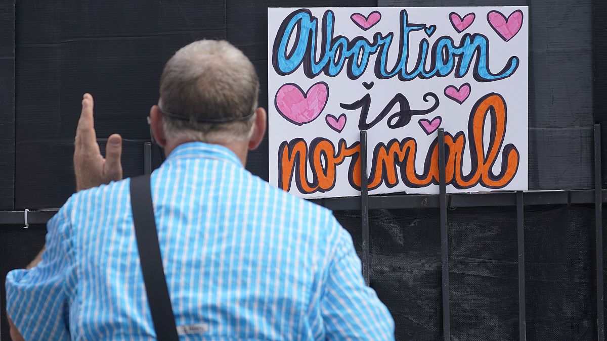 Un activista antiaborto frente a un cartel que dice que "El aborto es normal" fuera de la clínica de la Organización de Salud de la Mujer de Jackson, Mississippi, 30/6/2022