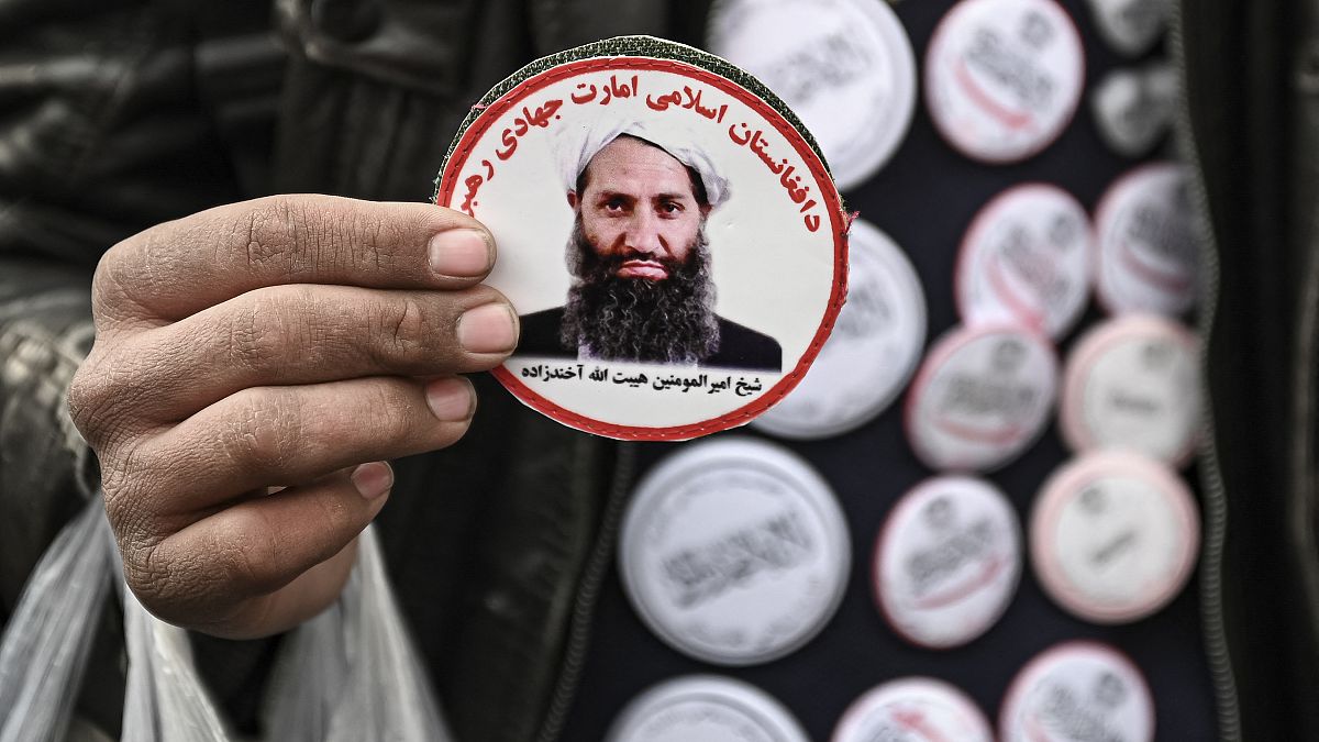 رجل من طالبان يحمل صورة أخوند زاده 