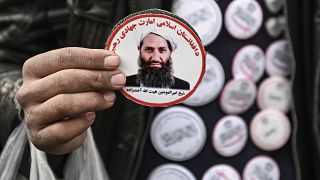 رجل من طالبان يحمل صورة أخوند زاده