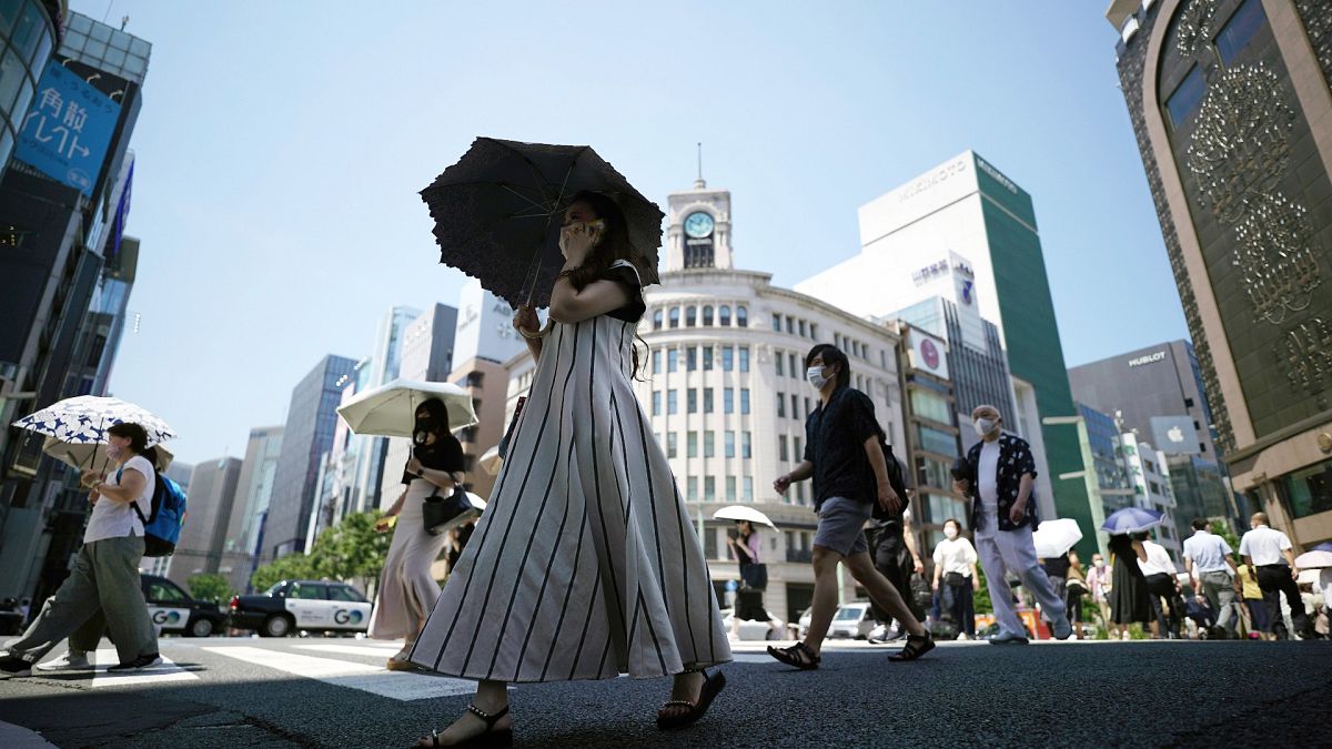 Japonya'nın başkenti Tokyo'da vatandaşlar, aşırı sıcaklardan korunmak için dışarıda şemsiye kullanıyor 