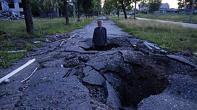 Viktor Shevchenko permanece en un cráter para mostrar su profundidad creada por un proyectil tras un ataque ruso en el distrito de Saltivka en Járkov, Ucrania. 01/07/2022