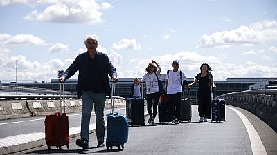 Пассажиры пешком добираются до терминала во время забастовки в аэропорту Шарль-де-Голль