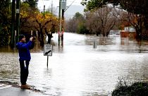 A man takes pictures of the flooded streets due to torrential rain in the Camden suburb of Sydney on July 3, 2022. 