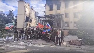 Russian troops including Chechens wave Russian and Chechen republic national flags in front of a destroyed building in Lysychansk, Ukraine, July 3, 2022.