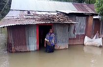 People standing in knee-deep water in front of their houses