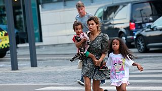 A woman and children flee the Field's shopping center after a shooting, in Copenhagen, Denmark, Sunday, July 3, 2022.