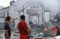 Des habitants devant des magasins détruits après une attaque à la roquette dans la ville ukrainienne de Sloviansk, 3 juillet 2022.