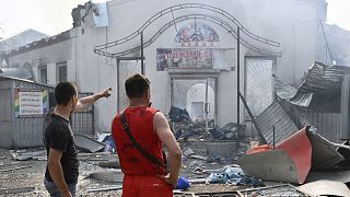 Des habitants devant des magasins détruits après une attaque à la roquette dans la ville ukrainienne de Sloviansk, 3 juillet 2022.