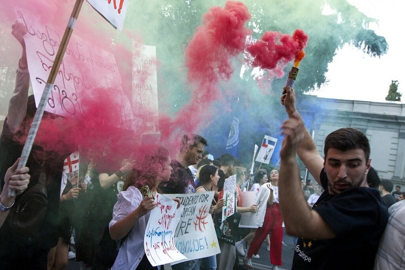 A demonstrator swings a flare during a pro-EU and anti-government Rally rally against in front of the Georgian Parliament in Tbilisi, July 2022