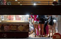 Prostitutes hide from riot police inside of a store during the eviction of a few activists who gathered at Puerta del Sol square in Madrid, Spain, in 2012