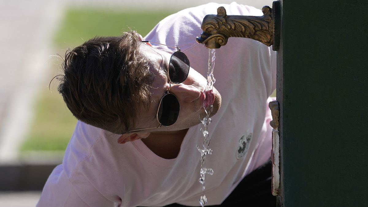 A tourist drinks water from a public fountain at the Sforzesco Castle, in Milan, Italy, Saturday, June 25, 2022.