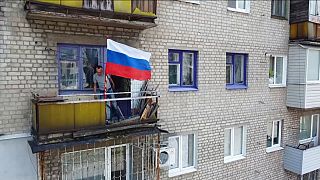 Ein Mann hisst eine Flagge auf einem Balkon in Lyssyschansk.
