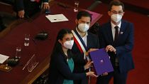 El presidente de Chile, Gabriel Boric, en el centro, sostiene el borrador final de una propuesta de nueva constitución