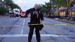 Αστυνομικός επιτηρεί την περίμετρο στο σημείο της επίθεσης με όπλο κατά τη διάρκεια της παρέλασης στο Ιλινόις