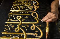 تطريز آية من القرآن الكريم  بخيوط ذهبية على نسخة طبق الأصل من كسوة الكعبة. 2022/06/15