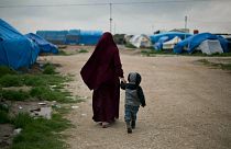 En esta foto de archivo de 2019, Samira, una ciudadana belga casada con un miembro francés del Estado Islámico, Karam El-Harchaoui, camina con su hijo en el campamento Roj
