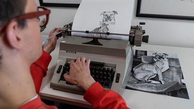 Artist James Cook using a typewriter to create a portrait of a dog