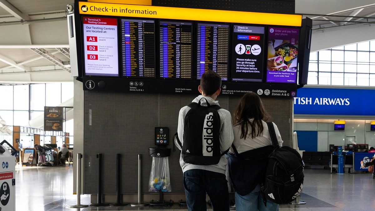 A couple looks at an electronic flight information board at Terminal 5 of London’s Heathrow Airport.