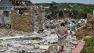 Une femme âgée marche à côté d'un bâtiment détruit par une frappe de missiles à Sloviansk, en Ukraine, mercredi 1er juin 2022.