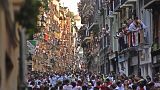 La gente corre por las calles delante de los toros de lidia durante el primer día de los encierros de las fiestas de San Fermín en Pamplona, el jueves 7 de julio de 2022